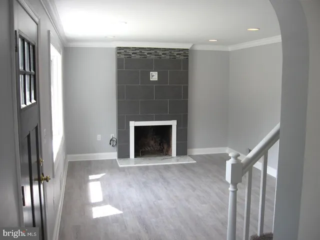 a view of an empty room with wooden floor and a fireplace