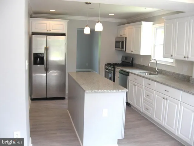 a kitchen with stainless steel appliances granite countertop a sink and a refrigerator