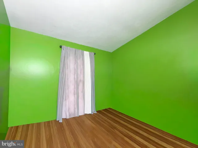 a view of an empty room with glass door and wooden floor