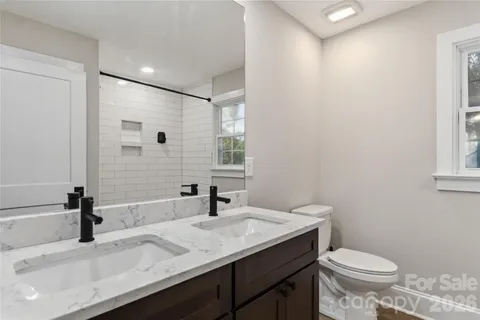 a bathroom with a granite countertop sink toilet and a mirror