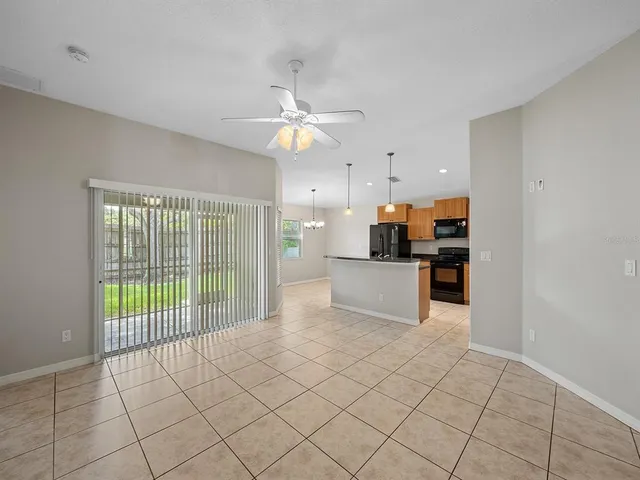 a view of an empty room and window and chandelier fan