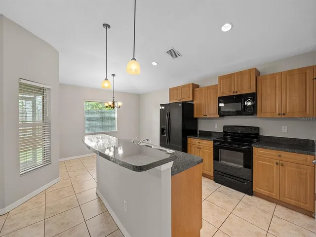 a kitchen with stainless steel appliances kitchen island granite countertop a refrigerator a stove and a sink