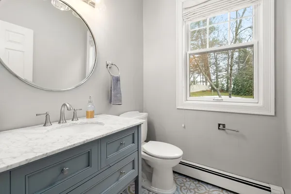 a bathroom with a granite countertop toilet a sink a mirror and a window