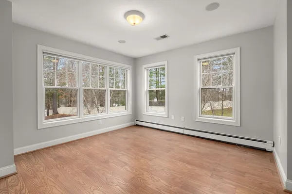 an empty room with wooden floor and windows