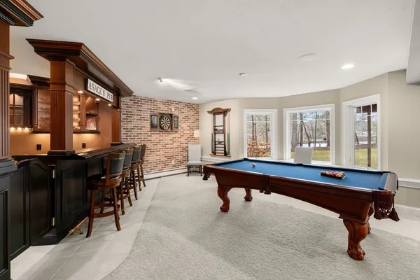 a living room with furniture pool table and large windows