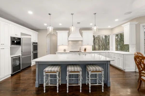 a kitchen with stainless steel appliances granite countertop a kitchen island hardwood floor and a sink