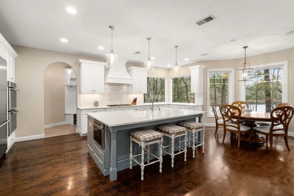 a kitchen with stainless steel appliances granite countertop wooden floors and table