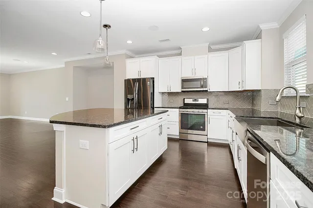 a kitchen with stainless steel appliances granite countertop a sink stove microwave and refrigerator