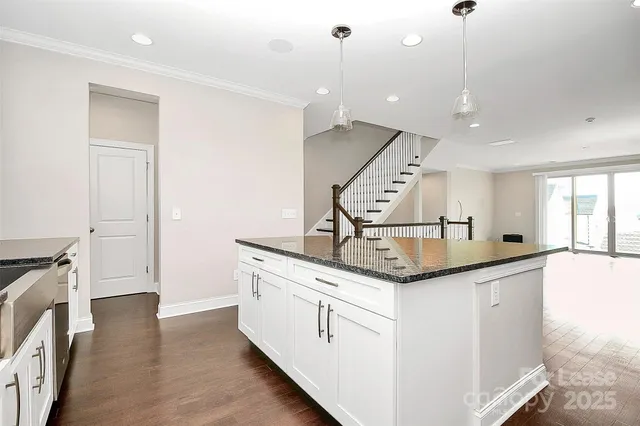 a kitchen with granite countertop a sink and stove with wooden floor