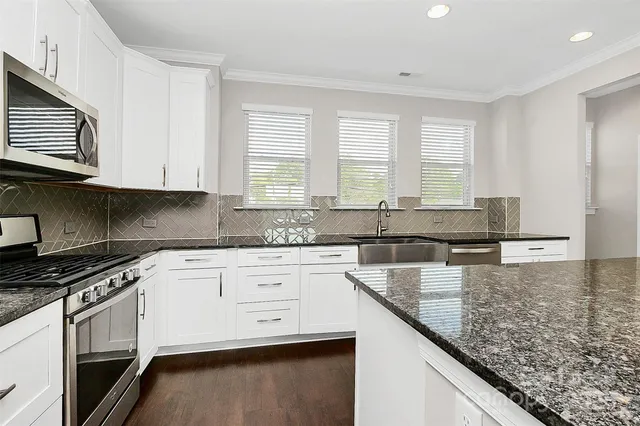 a kitchen with granite countertop a sink a stove and cabinets