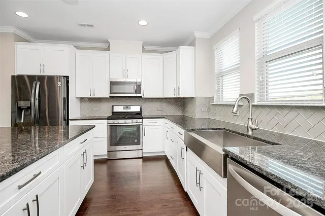 a kitchen with granite countertop a sink stainless steel appliances and window