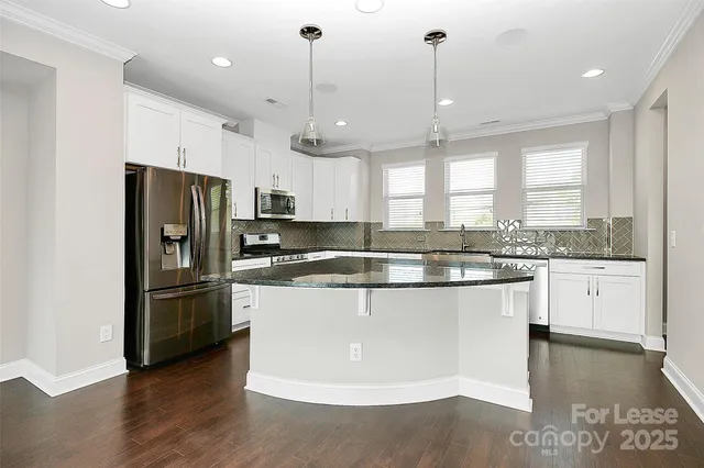 a kitchen with stainless steel appliances granite countertop a refrigerator a sink dishwasher a stove and white cabinets with wooden floor