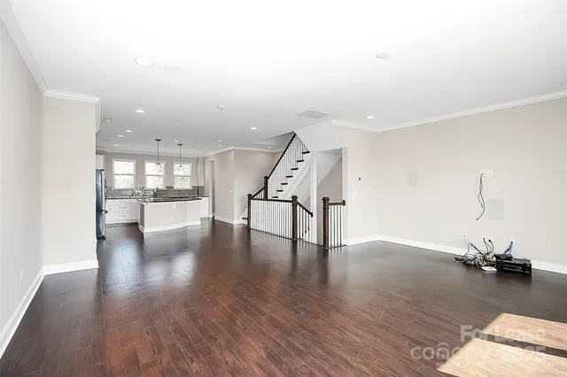 a view of a room with wooden floor staircase and a kitchen