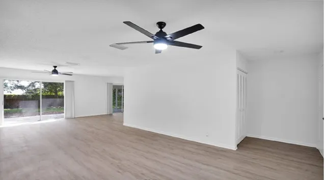 a view of a livingroom with a ceiling fan wooden floor and a ceiling fan