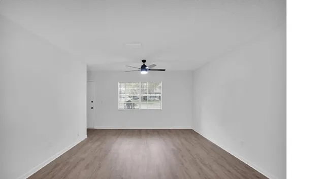 a view of an empty room with wooden floor and a window