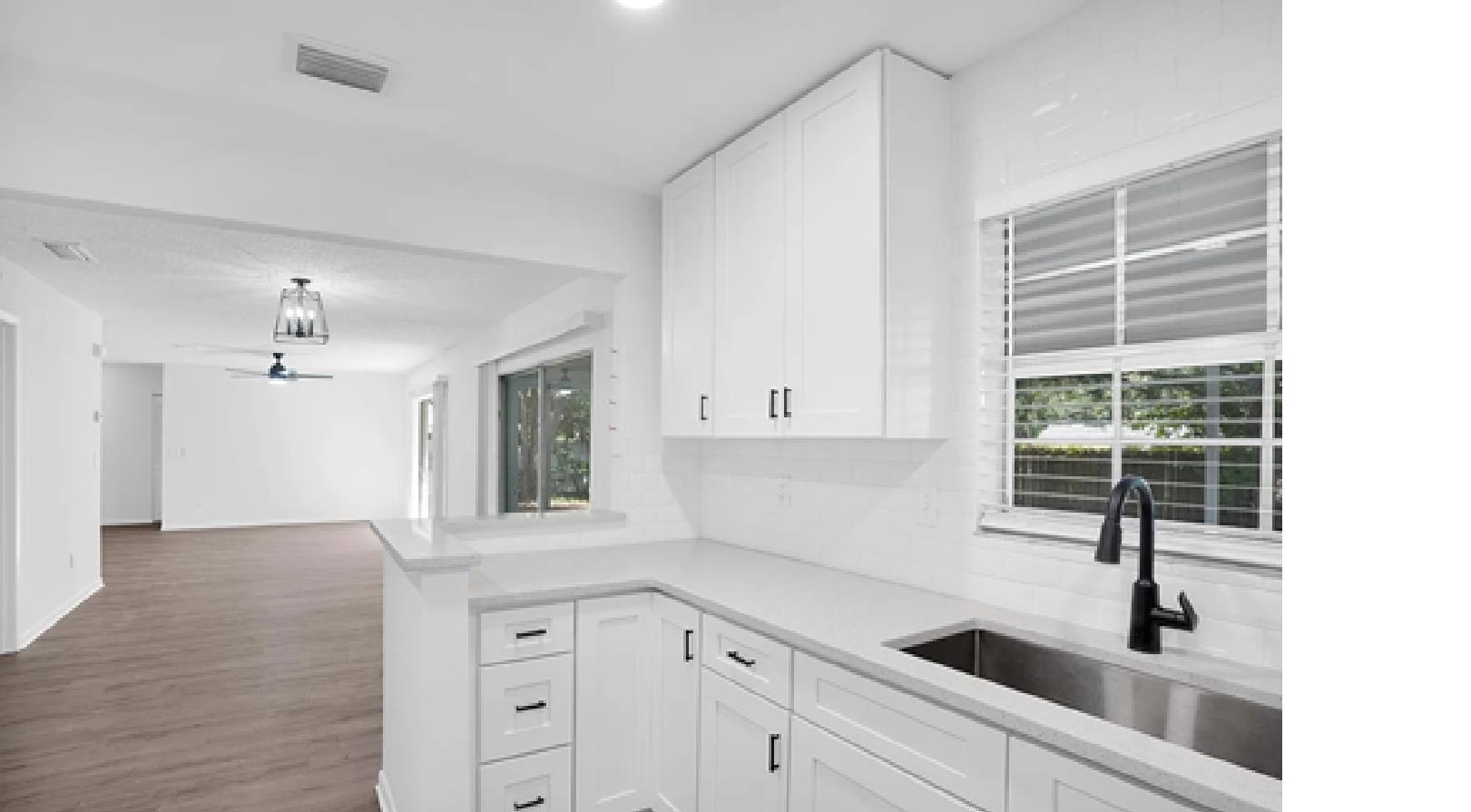 1010 San Remo Road St. Augustine, FL 32086 - Photo 66 of 67 Kitchen featuring white cabinets, open floor plan, light stone counters, dark wood-style floors, and a peninsula
