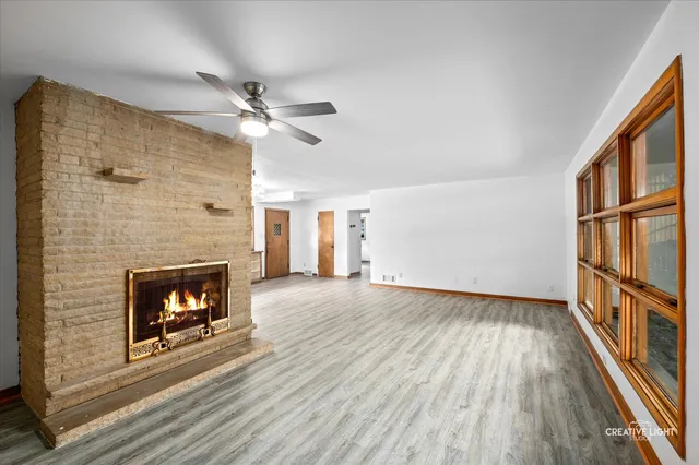 a view of an empty room with wooden floor fireplace and a window
