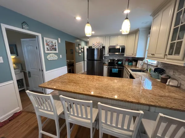 a kitchen with stainless steel appliances granite countertop a sink a stove a dining table and chairs