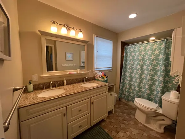 a bathroom with a double vanity sink toilet mirror and shower