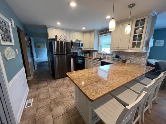 a kitchen with stainless steel appliances granite countertop a refrigerator a sink a stove a dining table and chairs