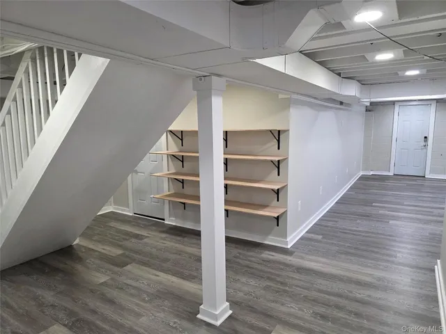 a view of an empty room with wooden floor and stairs