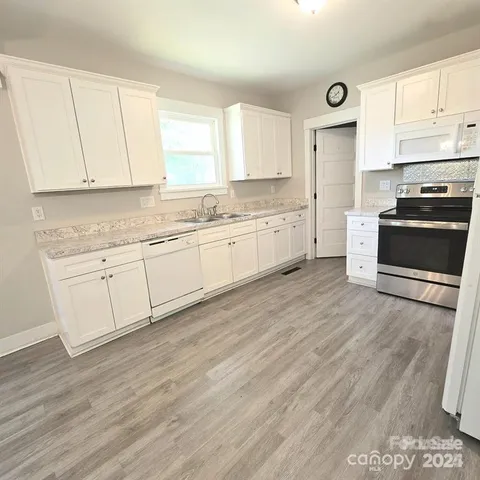 a kitchen with granite countertop white cabinets and white appliances
