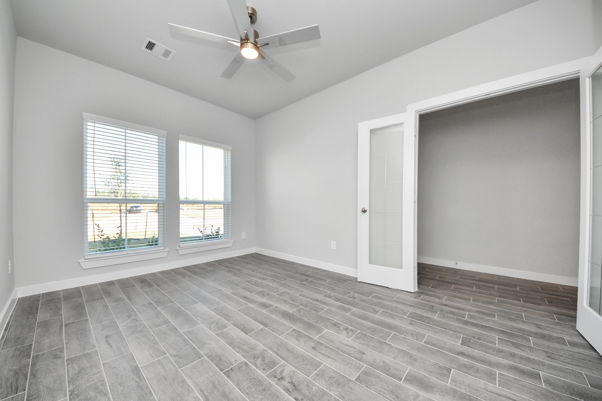 3002 Bury Park Dr Spring Spring, TX 77373 - Photo 6 of 45 Experience the perfect blend of sophistication and warmth in this home office, boasting elegant wood-look tile flooring and flooded with natural light from expansive windows and French doors.