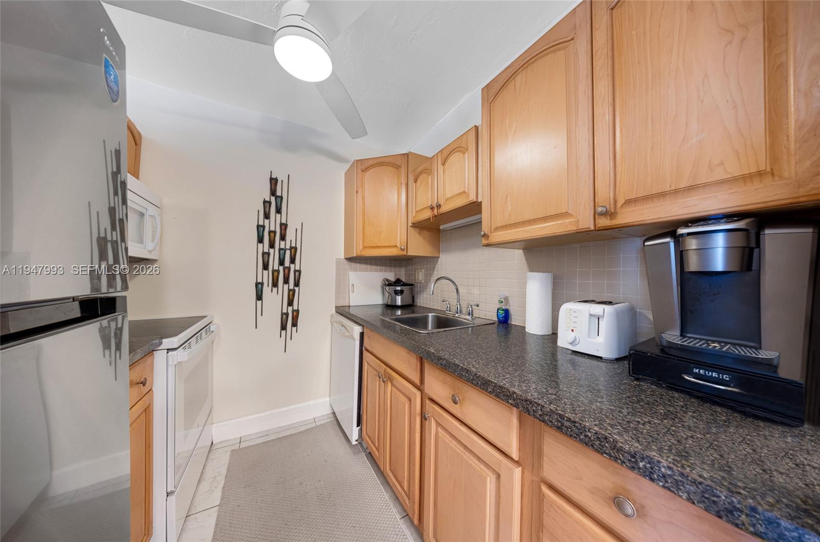 15610 Northeast 6th Avenue, Unit 9B Miami, FL 33162 - Photo 7 of 25 a kitchen with granite countertop a sink a stove and cabinets
