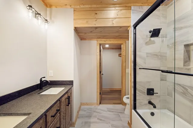 a bathroom with a granite countertop sink a mirror and shower