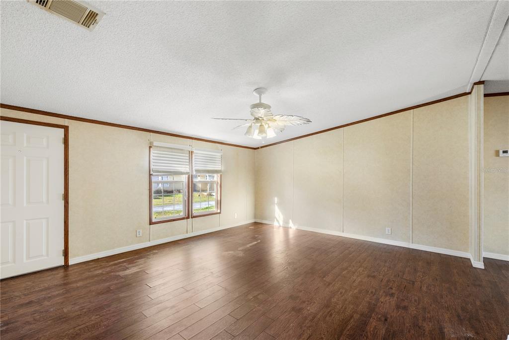 32443 Memory Lane Leesburg, FL 34788 - Photo 15 of 51 an empty room with wooden floor chandelier fan and windows