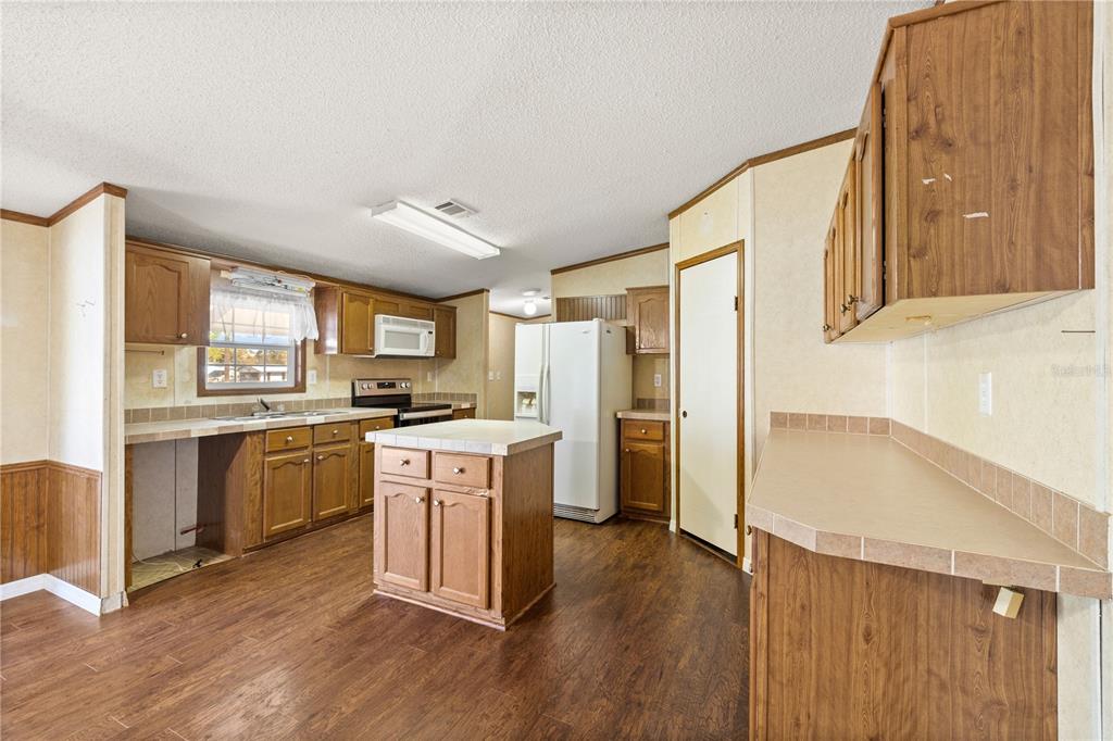 32443 Memory Lane Leesburg, FL 34788 - Photo 27 of 51 a kitchen with a refrigerator a stove top oven a sink and dishwasher with wooden floor
