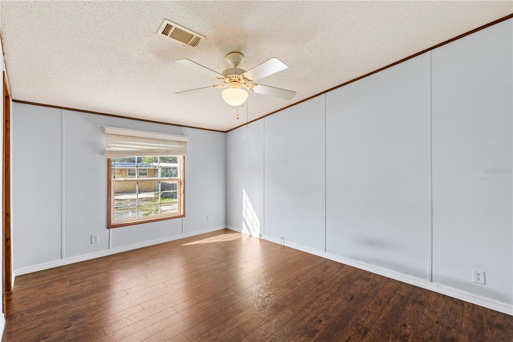 32443 Memory Lane Leesburg, FL 34788 - Photo 35 of 51 an empty room with wooden floor fan and windows