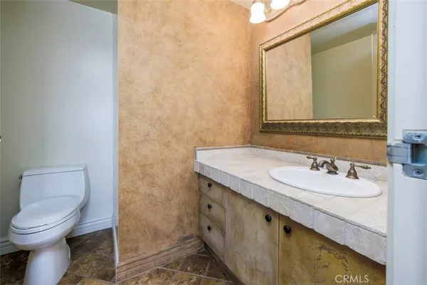 a bathroom with a granite countertop toilet sink and mirror