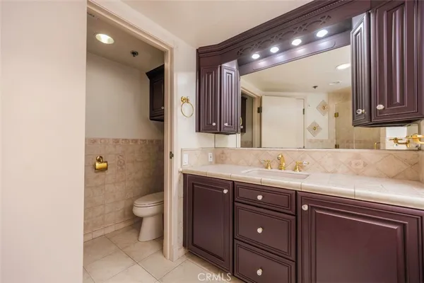 a bathroom with a granite countertop sink a toilet and a mirror