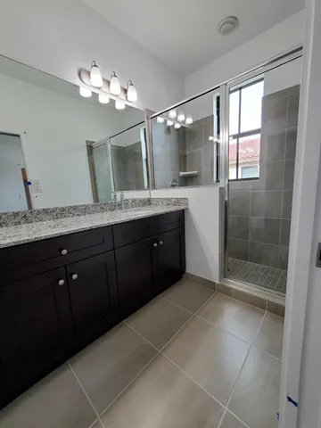 a spacious bathroom with a granite countertop sink a mirror and a shower