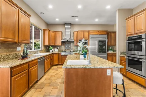 a kitchen with stainless steel appliances granite countertop a stove a sink and a refrigerator