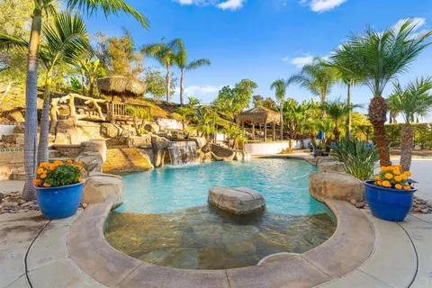a view of a swimming pool lawn chairs and a fire pit