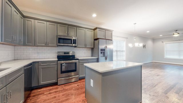 an empty room with wooden floor ceiling fan and windows