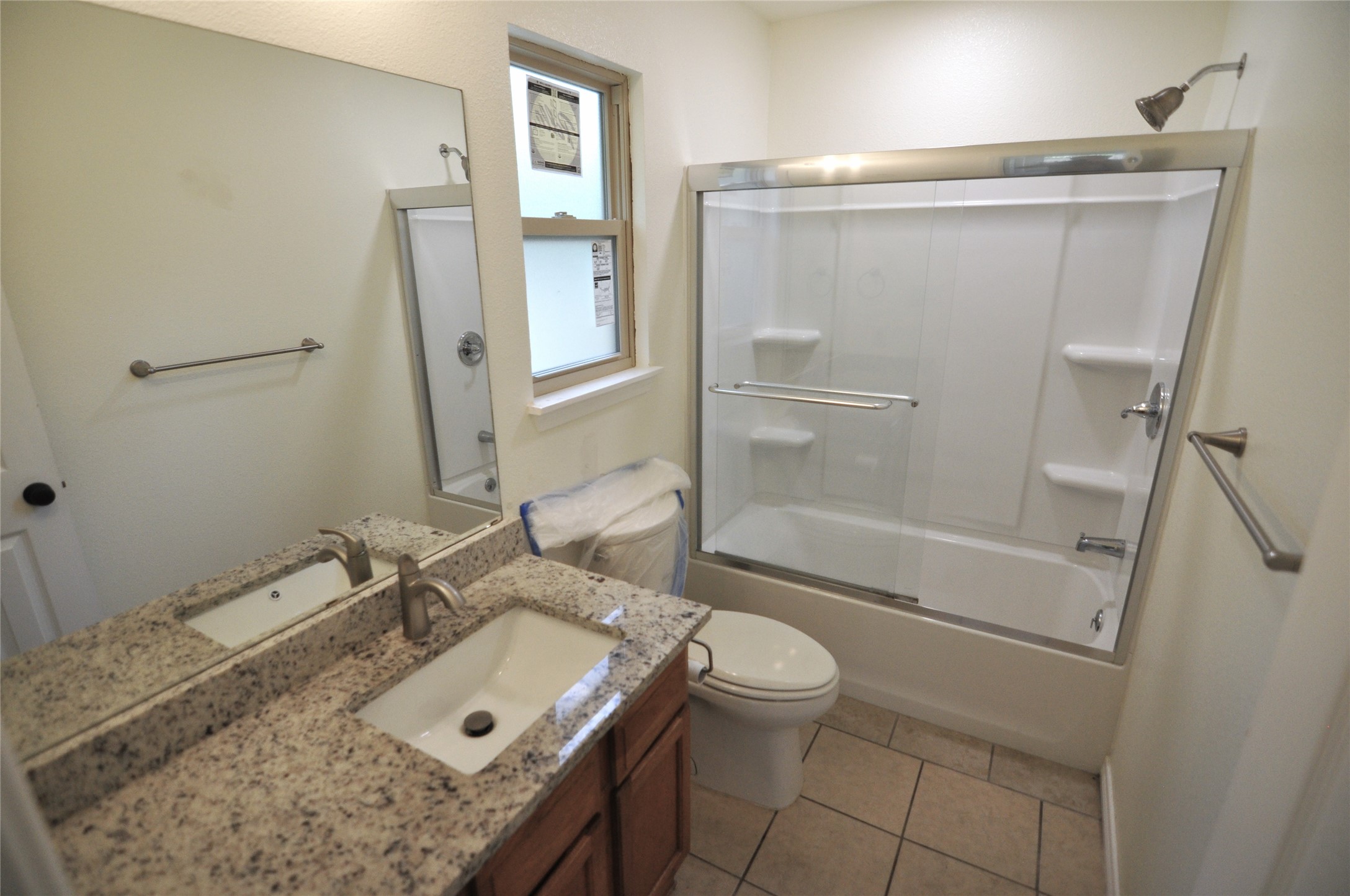 8809 Piney Point Drive, Unit B Austin, TX 78729 - Photo 10 of 10 Well-appointed bathroom showcasing a granite vanity and a modern tub with a glass-enclosed shower.