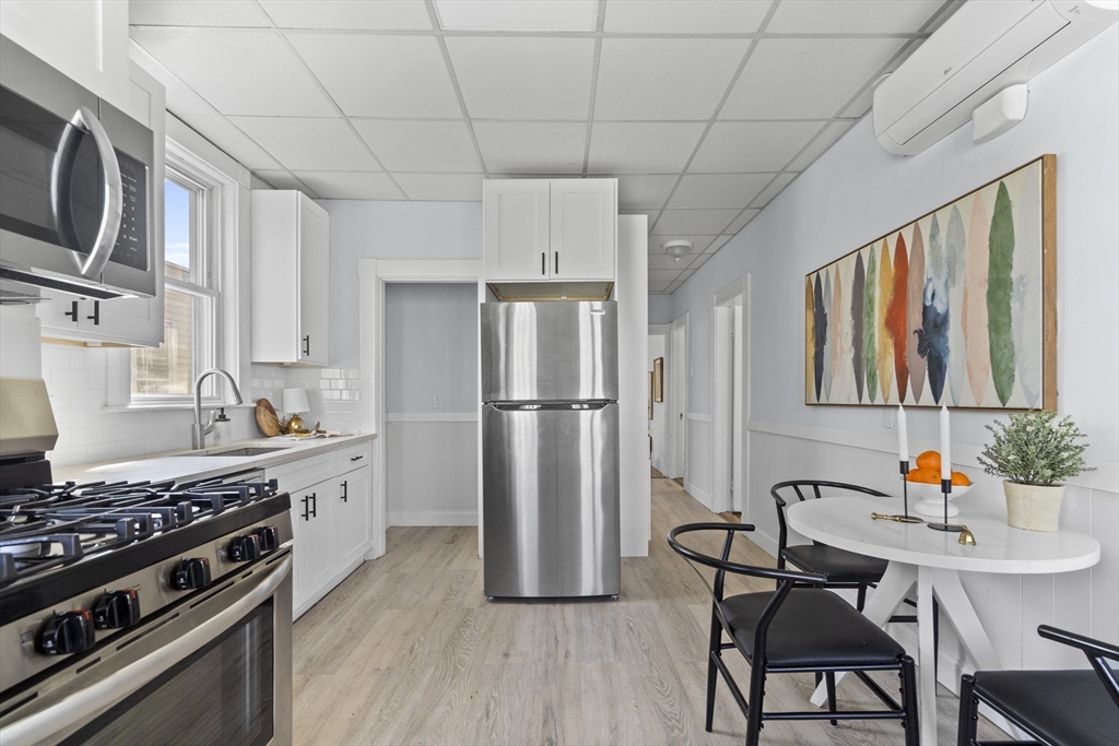 742 Bennington Street, Unit 3 Boston, MA 02128 - Photo 7 of 16 a kitchen with stainless steel appliances a refrigerator a stove a sink dishwasher and white cabinets with wooden floor