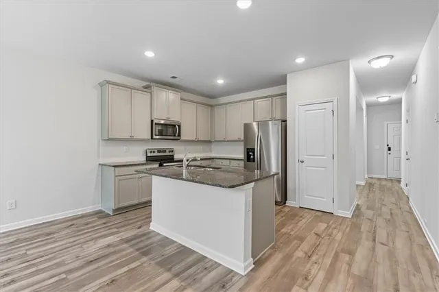 a kitchen with stainless steel appliances granite countertop a refrigerator and a stove top oven