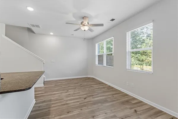 an empty room with wooden floor fan and windows