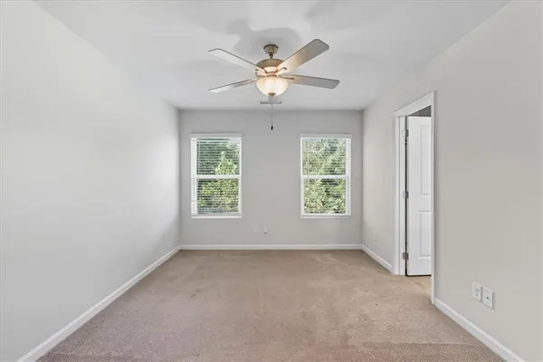 an empty room with windows and ceiling fan