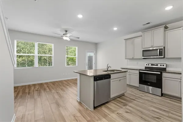 a kitchen with stainless steel appliances granite countertop hardwood floor sink stove and wooden cabinets