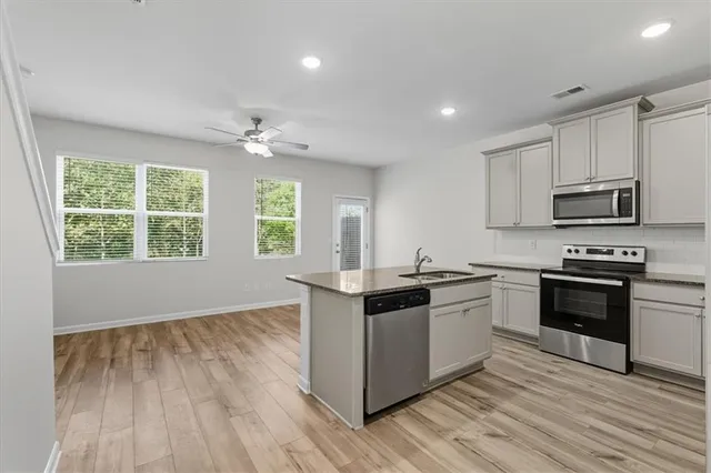 a kitchen with stainless steel appliances granite countertop hardwood floor sink stove and wooden cabinets