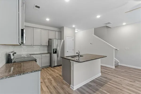 a kitchen with stainless steel appliances granite countertop a sink a stove and a refrigerator