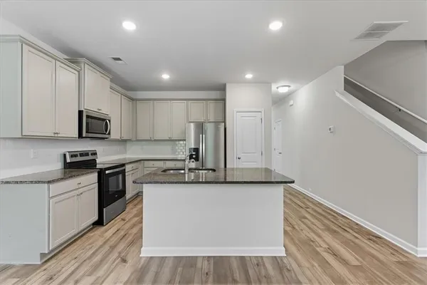 a large kitchen with stainless steel appliances granite countertop a stove a sink and a refrigerator