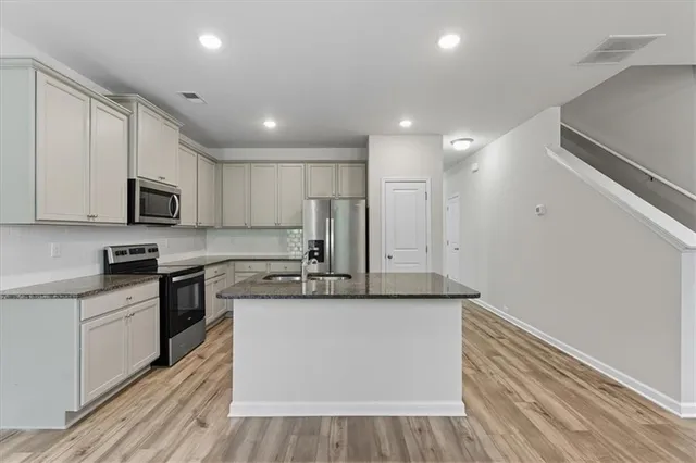 a large kitchen with stainless steel appliances granite countertop a stove a sink and a refrigerator