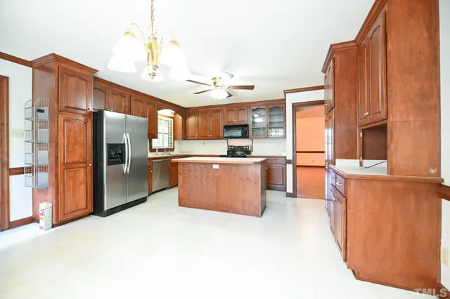 a large kitchen with stainless steel appliances kitchen island granite countertop a refrigerator a stove and a sink with wooden floor