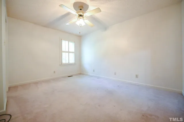 an empty room with a window and a fan